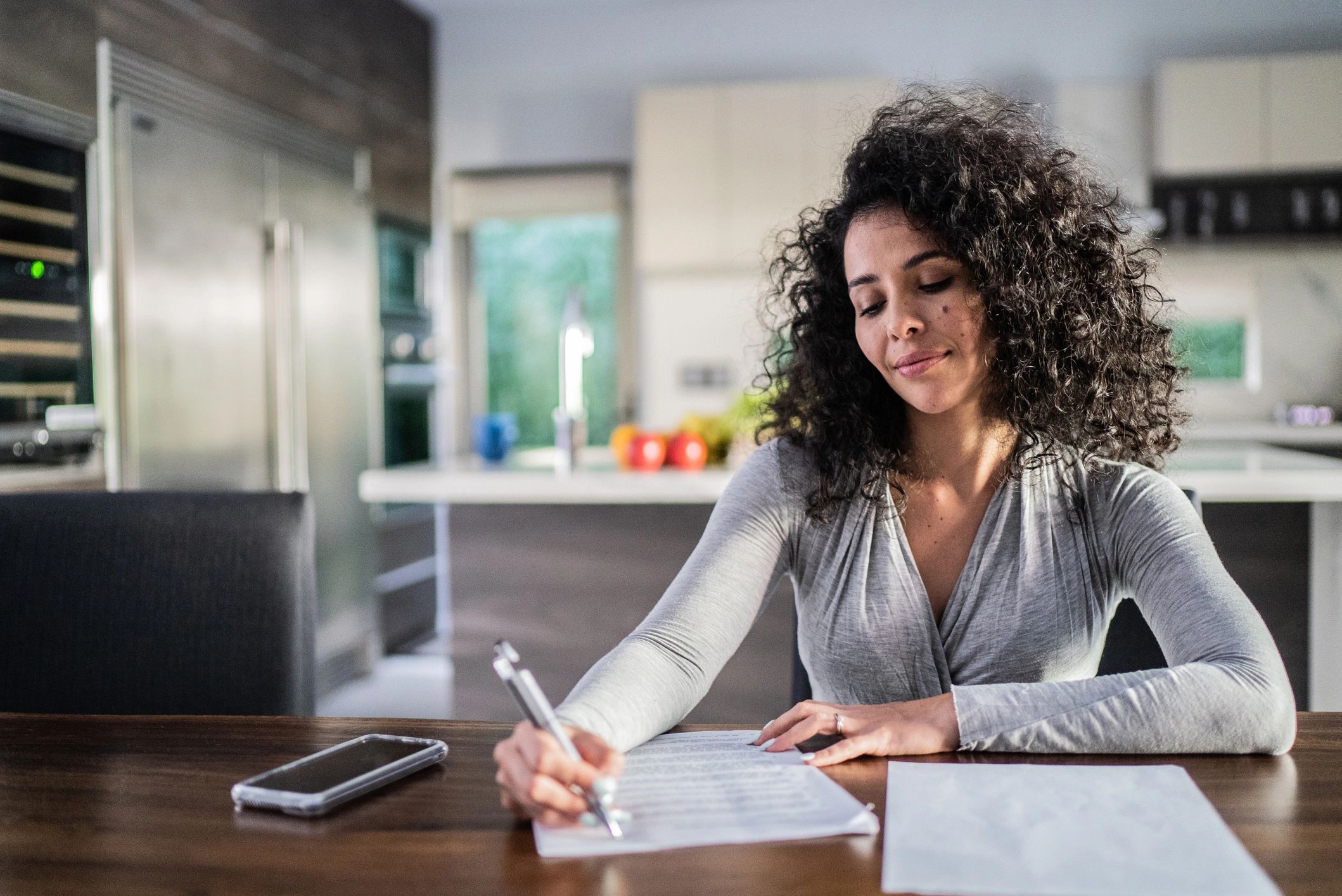 Mid adult woman filling document at home
